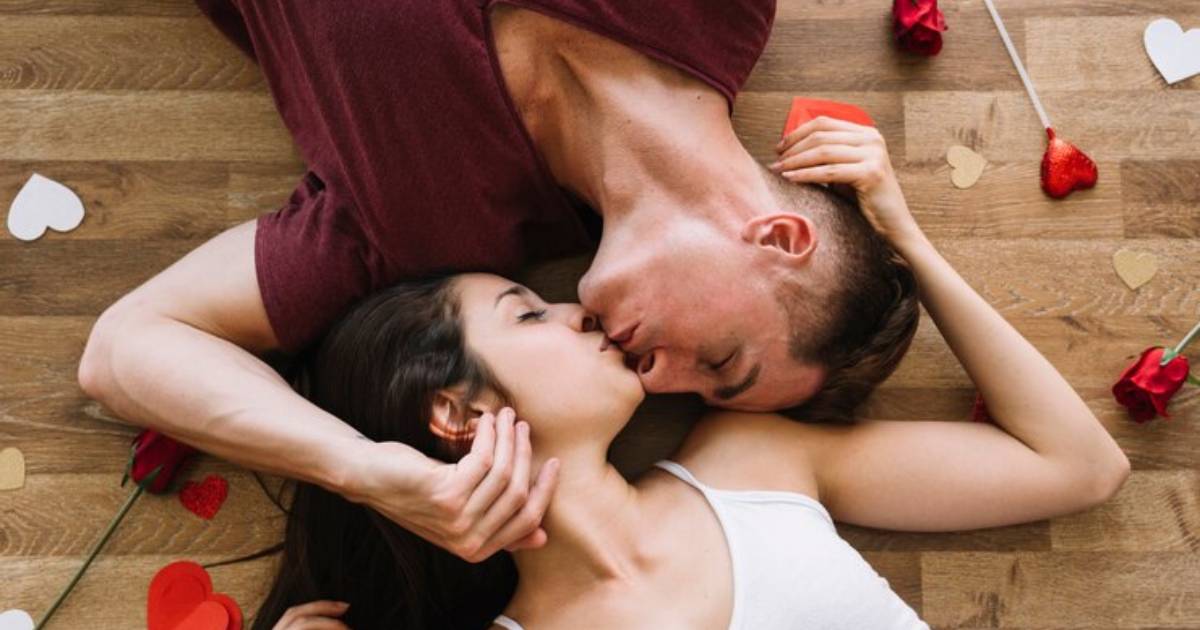 Casal deitado no chão se beijando enquanto pensam no tema "como fazer massagem".